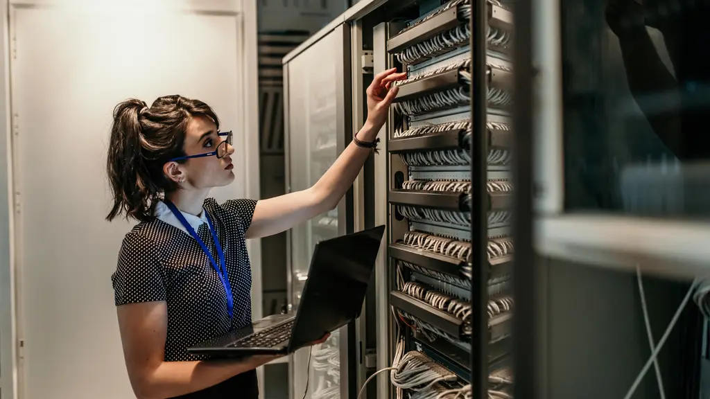 Engineer with a laptop checking equipment in a server rack